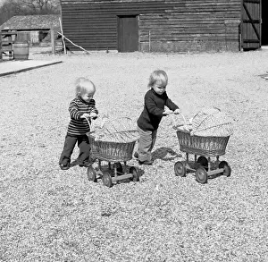 Two toddlers wheeling carry cots