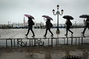 Tourists carrying umbrellas on temporary walkway, Venice