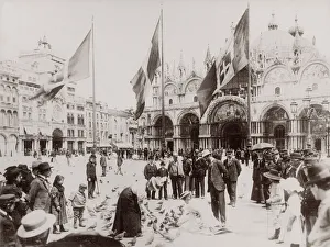 Tourists feeding pigeons in St Marks Square, Venice, Italy