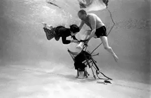 Underwater escapologist - a boy dives into a swimming pool to help a man untie himself from a chair. (2 of 3) Date: 1967