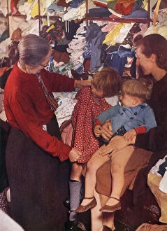 Images Dated 10th August 2020: A W. V. S. worker selecting a frock for a little girl