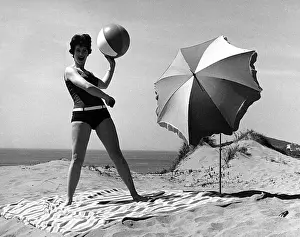 Woman on beach with ball and sunshade