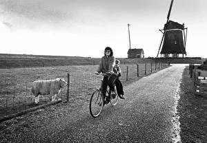 A woman cycles past the Oudeschild windmill on the island of A woman cycles past the Oudeschild windmill on the island of