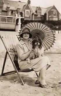 Woman with dog and parasol on a beach