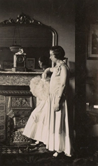 Images Dated 31st March 2017: Woman in evening dress standing by a fireplace