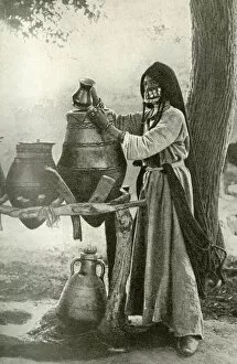 Woman in face veil drawing water from a jar, Egypt