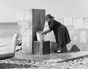 Shingle Prints: Woman filling a bucket from an outdoor tap