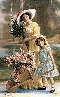 Woman and girl with flowers in a wheelbarrow