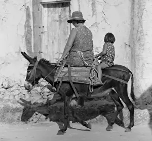 Woman and girl riding a small donkey