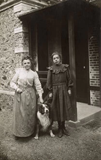 Woman and girl with sheepdog outside a house, France