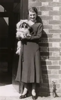 Pekingese Prints: Woman with Pekingese dog outside a house