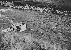 Suspended Prints: Woman pushing box across river