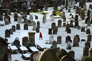 Cold Gallery: Woman in red coat in Kirkcudbright snowy graveyard
