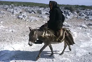 Dust Prints: Woman riding a donkey along a country lane, Yugoslavia