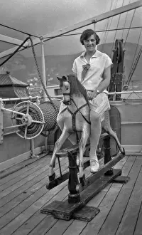 Woman riding a hobby horse on board ship