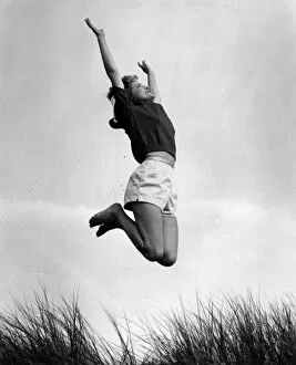 Images Dated 18th November 2016: Woman in shorts and top jumping in sand dunes