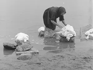 Woman sorting out washing in a river
