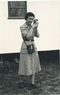 A woman using what looks to be a cine camera, probably a Bell and Howell 252