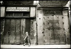 Woman walking in front of boarded up shops, Valencia, Spain