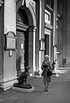 Woman walks past bronze dog, London