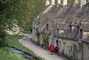 A woman walks past stone cottages in the village of Bilbury