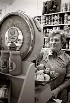 Grocers Gallery: Woman weighing fruit on scales in a shop