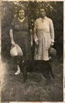 Two women with a dog in a garden