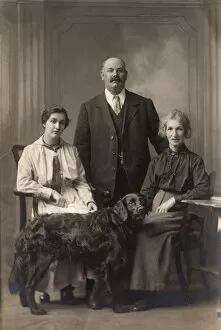 Two women and a man with a Flat-Coated Retriever
