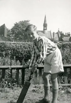 A Young boy playing cricket in a suburban garden - he awaits for a delivery to arrive A Young boy playing cricket in a suburban garden - he awaits for a delivery to arrive