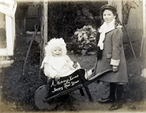Touching Prints: Young girl with her baby sister in a small wheelbarrow - A Merry Christmas card