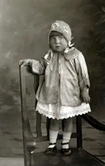 Pinafore Prints: Young girl posing for studio photograph standing on a chair