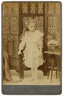 Panels Prints: Young girl in studio photo with ornately carved wooden screen behind her Date: circa 1910s