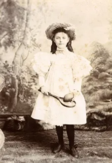 Images Dated 5th November 2018: Young Girl in a white dress holding a small racquet and ball