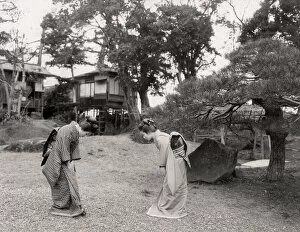 Two young Japanese women bowing to each other, greeting
