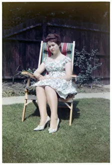 Insert Collection: A young lady sat in a neat garden in a canvas-backed chair