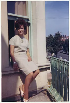Images Dated 4th February 2021: Young lady seated on exterior window ledge - seaside hotel