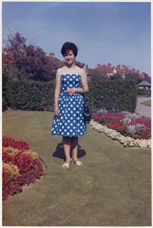 Young lady standing between beautifully-manicured flowerbeds