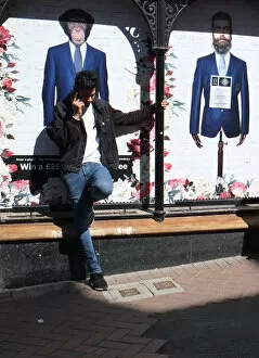 Images Dated 22nd July 2019: A young man in jeans sits against a fashion shop window