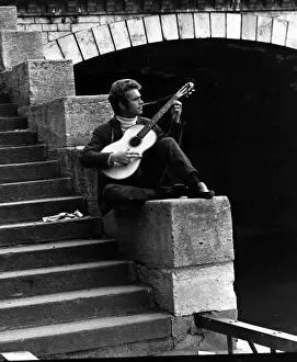 Concentrating Prints: Young man playing guitar near a bridge