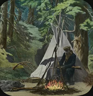 Wigwam Gallery: Young man sits by fire outside his teepee in the woods