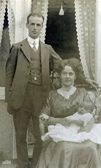 A young middle class couple pose for a photograph with their new little baby