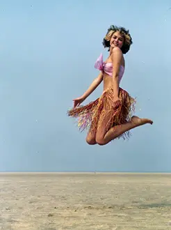 Young woman jumping in a grass skirt, West Country