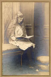 Leaded Prints: Young woman with long hair in a window seat reading a book Date: circa 1910s