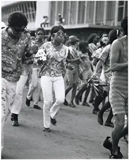 Sunglasses Prints: A young woman in trendy sunglasses dances with her friends at the Port of Spain Carnival