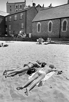 Two young women in bikinis sunbathe - Tenby Harbour, Wales