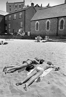 Images Dated 13th June 2019: Two young women in bikinis sunbathe - Tenby Harbour, Wales